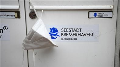 Eine FFP2-Maske hängt am Eingang zum Bürgerbüro Mitte in Bremerhaven. 