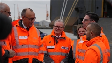 Bundeskanzler Friedrich Merz spricht im Bremerhavener Hafen mit einem Mitarbeiter.