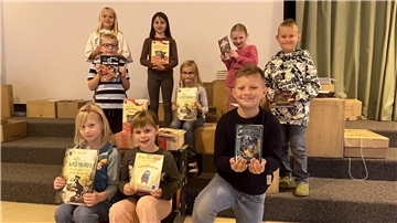 Zum Weltkindertag: 600 Bücher für Grundschulkinder in der Wurster Nordseeküste Neun Kinder halten ein Buch und freuen sich.