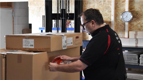 Ein Mann klebt einen Versandsticker auf ein Paket.