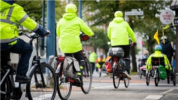 Stadtradeln 2025: Bremerhaven erreicht neuen Kilometerrekord Mehrere Radfahrende in leuchtend gelben Warnjacken fahren in einer Gruppe durch eine Stadt. Auch ein Polizei-Radfahrer und ein Liegerad mit Wimpel sind zu sehen.