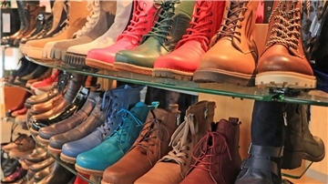Viele bunte Boots stehen in einem Schuhregal. 