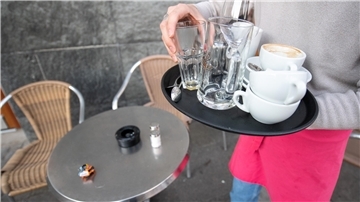 Eine Kellnerin räumt den Tisch eines Restaurants ab.