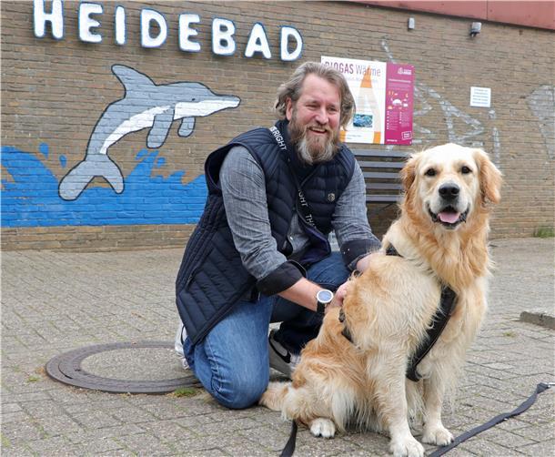 Wenn die Badesaison für Menschen endet, dann sind die Vierbeiner dran Ein Mann hockt mit seinem Hund auf dem Boden