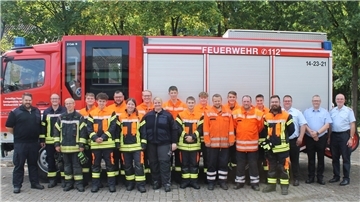 Feuerwehrleute stehen vor einem Einsatzfahrzeug der Feuerwehr