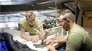 Zwei Männer beugen sich über eine Industrienähmaschine