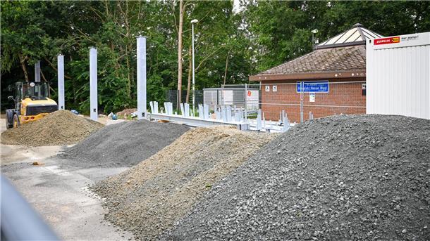 Strom für unterwegs: Rastplätze Nesse Ost und West an A27 bekommen Ladesäulen Schotterhaufen und Baufahrzeug vor einem Autobahn-Toilettenhäuschen