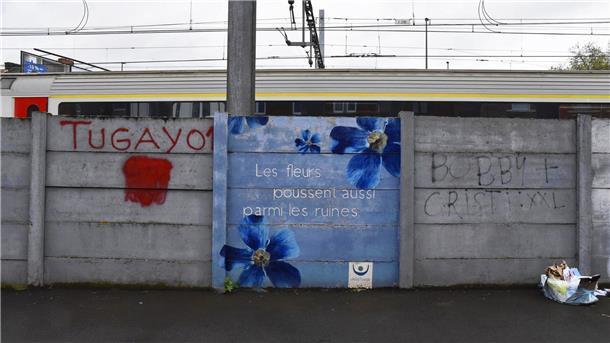 Auf dem Wandbild steht auf Französisch: „Auch zwischen den Ruinen wachsen Blumen.“
