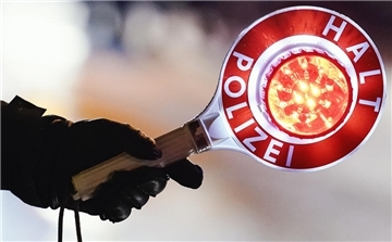 Das Foto zeigt eine Hand, die eine Polizeikelle hält.