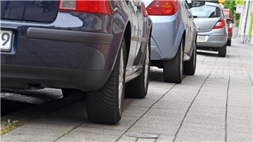 Auf Gehwegen parkende Autos versperren Rollstühlen oder Kinderwagen häufig den Weg. (Symbolbild)