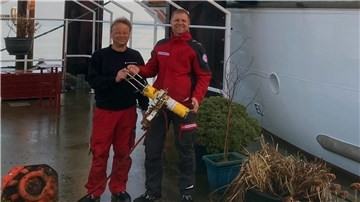 Vormann Ralf Sarközy und Maschinist Kai Schöps präsentieren ihr Fundstück vor dem Seenotrettungskreuzer „Anneliese Kramer“