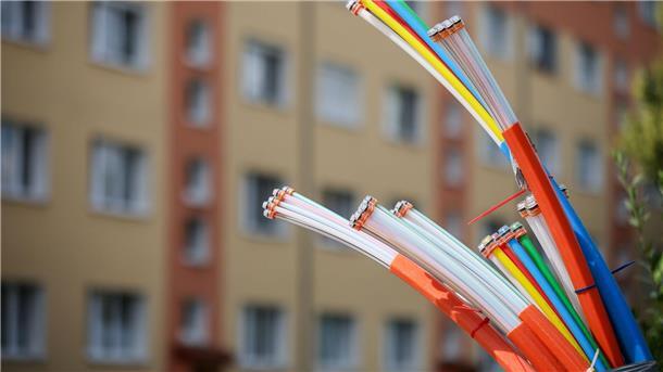 Aus dem Sockel eines Schaltschranks ragen Glasfaserkabel heraus. Beim Breitbandausbau sieht die Lage inzwischen deutlich besser aus als noch vor zwei Jahren.