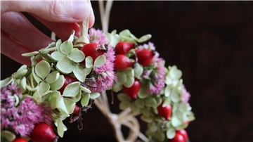 Hand hält Blumenkranz