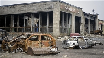 Ausgebrannte Autos stehen vor einem Autohaus, das durch russischen Beschuss in Isjum zerstört wurde.