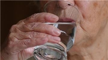 Person trinkt aus Wasserglas
