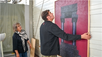 Ein Mann und eine Frau hängen ein Gemälde an die Wand.