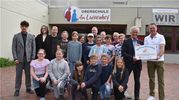 Das Foto zeigt die Übergabe der Plakette vor der Oberschule am Luisenhof.