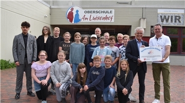 Das Foto zeigt die Übergabe der Plakette vor der Oberschule am Luisenhof.