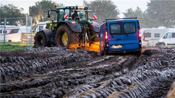 Nach Einlassstopp beim Wacken: Viele Fans müssen verärgert die Heimreise antreten Autos werden mit Hilfe eines Traktors auf das Gelände des Heavy-Metal-Festivals in Wacken durch den Schlamm gezogen.