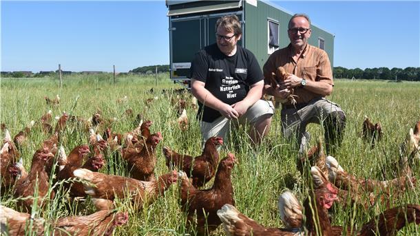 Das Bild zeit Landwirt Hans Peter Meinke und Bäckermeister inmitten einer Hühnerschar.  