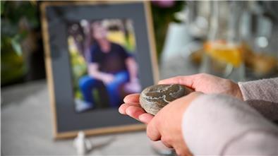 Barbara Schmidt (Name geändert) hält einen gravierten Stein in den Händen. Er gibt ihr Kraft, während sie über die Krebserkrankung ihres verstorbenen Mannes spricht.