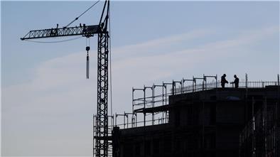Bauarbeiter stehen auf der Baustelle eines Mehrfamilienhauses.