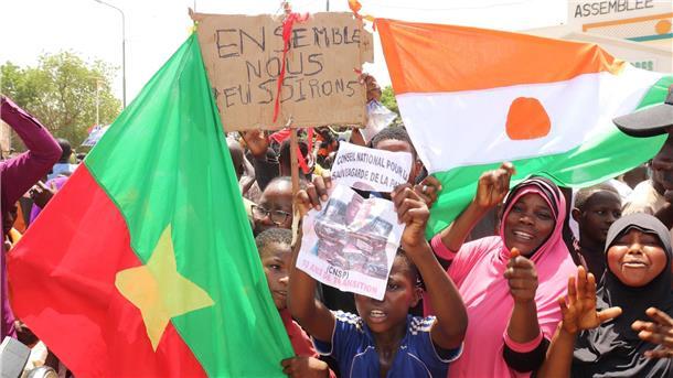 Befürworter des Putschs halten eine Flagge von Burkina Faso (l) und Niger hoch. Die beiden Länder haben einen Pakt geschlossen.