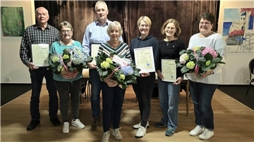 Geehrte Mitglieder des TuS Schwei mit Urkunden und Blumensträußen