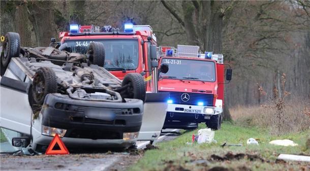 Zwei Feuerwehrwagen und ein beschädigter PKW, der auf dem Dach liegt.