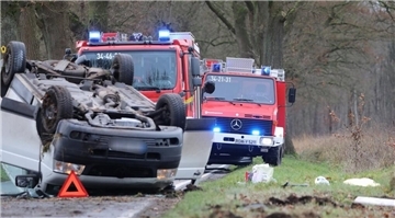Zwei Feuerwehrwagen und ein beschädigter PKW, der auf dem Dach liegt.