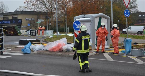 Menschen in orangen Anzügen stehen auf einer Straße.