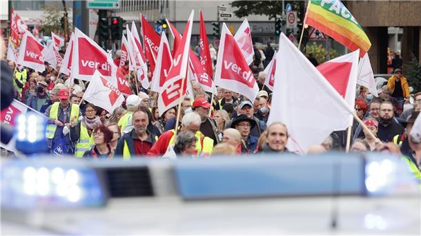 Bei der Demonstration in Düsseldorf gehen Teilnehmer mit Flaggen eine Straße entlang. Die Kundgebung wird von der Polizei begleitet.