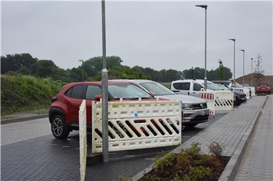 Das Foto zeigt den Parkplatz. Die Leuchten auf der Stellfläche werden durch Absperrgitter geschützt.  
