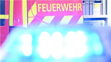 Viele Verletzte nach Busunfall in Bremerhaven - Großeinsatz für Feuerwehr  Ein Fahrzeug der Feuerwehr steht bei einem Einsatz auf einer Straße, während im Vordergrund das Blaulicht eines Polizeifahrzeugs zu sehen ist.