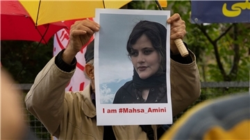 Bei einem Protest in Berlin hält ein Mann ein Bild der verstorbenen Mahsa Amini in Händen.