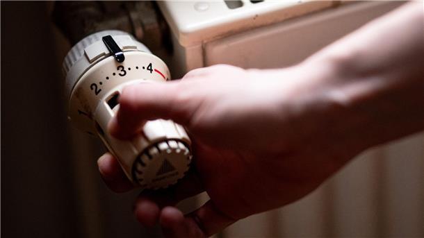 Jemand dreht am Thermostat eines Heizkörpers.