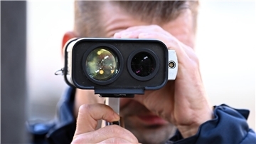 ein Polizist kontrolliert per Lasermessung die Geschwindigkeit von Fahrzeugen
