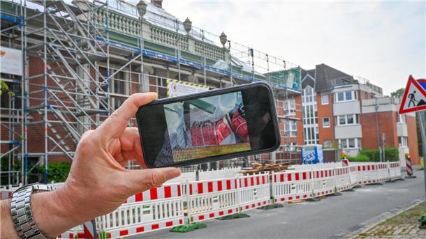 Alarmismus oder begründete Sorgen? Wie eine Baustelle für Unmut sorgt Ein Handy, im Hintergrund ein Haus mit Baugerüst.