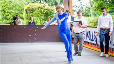 Sportler in Rollschuhen auf Betonbahn, dazu Zuschauer.