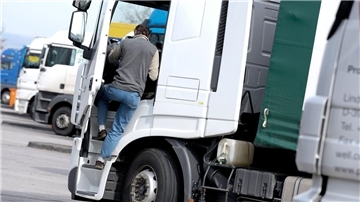 Ein Mann steigt in die Fahrerkabine eines Lkw.