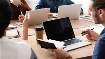 Menschen an einem Tisch, ein Kaffeebecher und Laptops sind zu sehen. Beim Netzwerktreffen am 27. Mai in Langen stehen Austausch, Fachkräftesicherung und gezielte Fördermöglichkeiten im Mittelpunkt – Programme wie „Kompass“ verbinden Selbstständige und Unternehmen mit passender Weiterbildung.