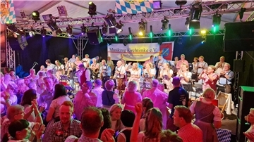 Das Foto zeigt feiernde Menschen in einem Festzelt. 