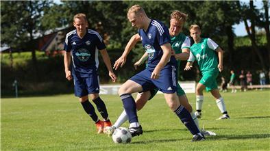 Zwei Männer kämpfen auf einem Rasen um einen Fußball