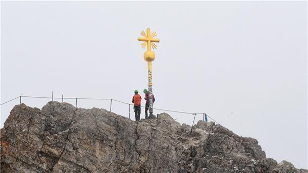 Das ist der Gipfel - das Kreuz mit dem Kreuz Bergsteiger stehen neben dem Gipfelkreuz des Zugspitzgipfel.