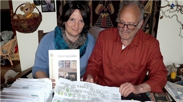 Berit und Hartmuth Seitz mit den unzähligen E-Mails (links im Foto), die sich bei der Konversation zum „Spurenpuzzle“ ausgedruckt angesammelt haben.