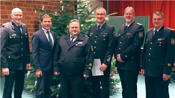 Sechs Männer in Anzug oder Uniform vor einem Weihnachtsbaum