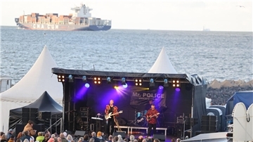 Besucher genießen den Sound von Mr. Police vor der malerischen Kulisse der Elbmündung in Cuxhaven.