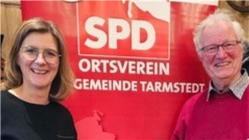 Ein Mann und eine Frau stehen vor einem SPD-Plakat.