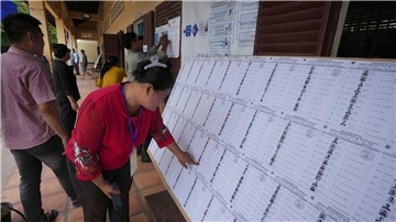 Bewohner von Phnom Penh sehen sich vor der Stimmabgabe in einem Wahllokal eine Registrierungsliste an.