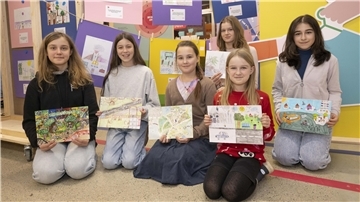 Die sechs Gewinnerinnen des Malwettbewerbs knien vor einer Ausstellungswand und zeigen ihre Gemälde